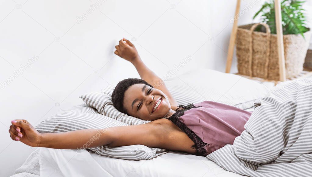 African american girl stretching her body in bed