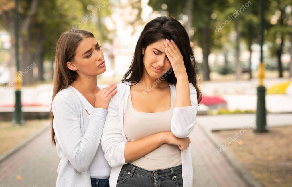 Girl Comforting Desperate Female Friend Standing Outdoor In Park