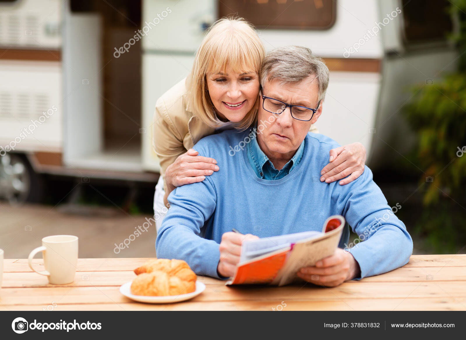 Mature woman helping her husband solve crossword puzzle near trailer Mature woman helping her husband solve crossword puzzle near trailer