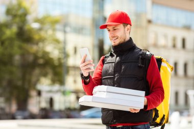 Pizza kutulu kurye telefon kullanarak şehre yiyecek getiriyor.