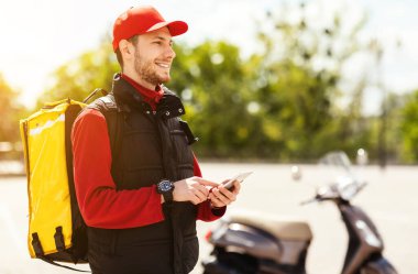 Yemek Teslimatı Kuryesi Smartphone kullanarak Scooter 'da yemek dağıtıyor.