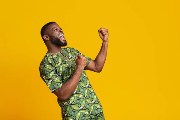 Super glad afrikansk kille firar framgång över gul bakgrund — Stockfoto