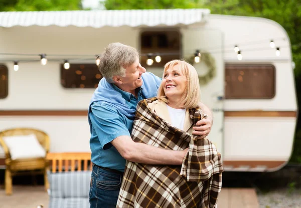 Caring senior man covering his beloved woman with blanket near motorhome at camping site — Stock Photo, Image