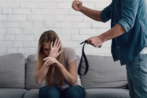 Slaan en vernedering. Man bedreigt met vuist naar vrouw, sluit gezicht met handen — Stockfoto