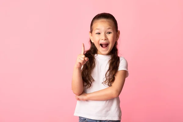 Excited asian girl has great idea and points up