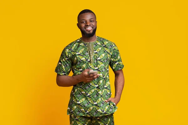 Sorrindo cara negro em traje africano usando telefone celular — Fotografia de Stock