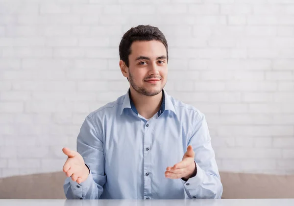 Freundlicher Mann deutet mit den Händen auf leeren Raum, sitzt auf Sofa im Innenraum — Stockfoto