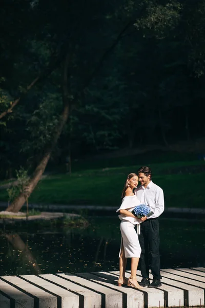 Влюбленная пара обнимается на мосту у озера в прекрасном парке — стоковое фото
