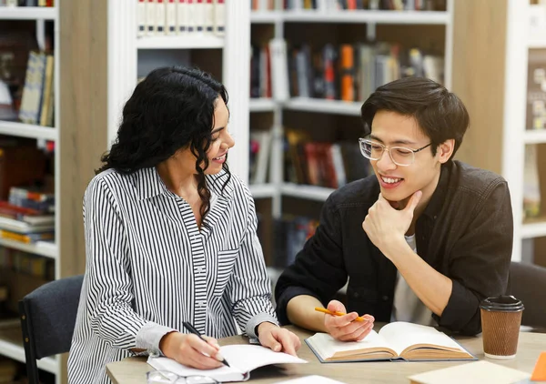 Couple multiculturel faisant ses devoirs dans une bibliothèque publique — Photo