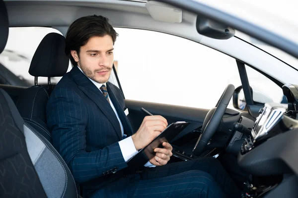 Professioneller Autoverkäufer sitzt im Auto und notiert im Autohaus — Stockfoto