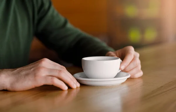 Mãos de homem segurando xícara de café, café interior — Fotografia de Stock