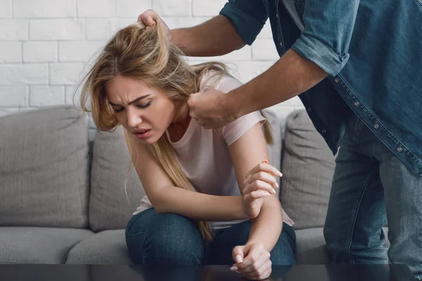 Homem ameaça mulher por agarrar seu cabelo, cara de menina expressa dor — Fotografia de Stock