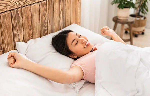 Mujer coreana bien dormida despertando estirándose acostada en la cama interior — Foto de Stock