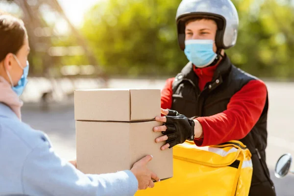 Courier em máscara médica dando lancheiras para menina ao ar livre — Fotografia de Stock