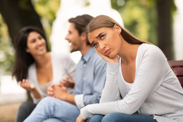 Depressief meisje zitten naast gelukkig vrienden in park buiten — Stockfoto