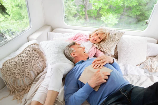 Щаслива зріла жінка і її чоловік розслабляються на ліжку в автономному будинку під час кемпінгу відпустки — стокове фото