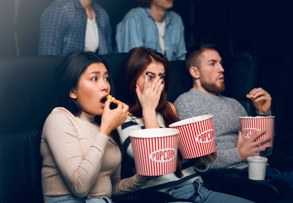 Young people scared of horror movie in film theater