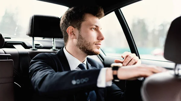 Businessman sitting in luxury car looking out of window