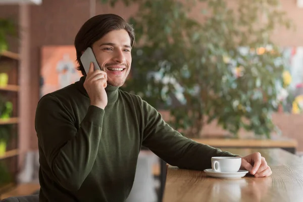 Hombre emprendedor sonriente hablando con los clientes en la cafetería, usando el teléfono —  Fotos de Stock