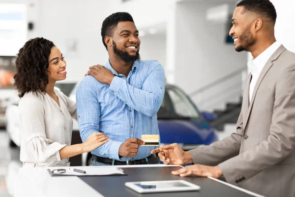 Casal alegre que dá o cartão de crédito ao vendedor automático no negócio — Fotografia de Stock