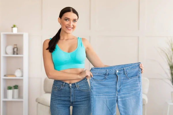 Mulher comparando jeans após perda de peso em casa — Fotografia de Stock