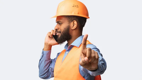 Trabalhador da construção falando sobre celular Gesturing para esperar, fundo branco — Fotografia de Stock