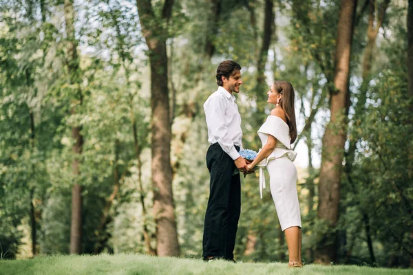 Свадебная пара, объявившая о любви, держась за руки, стоящие в парке под открытым небом — стоковое фото