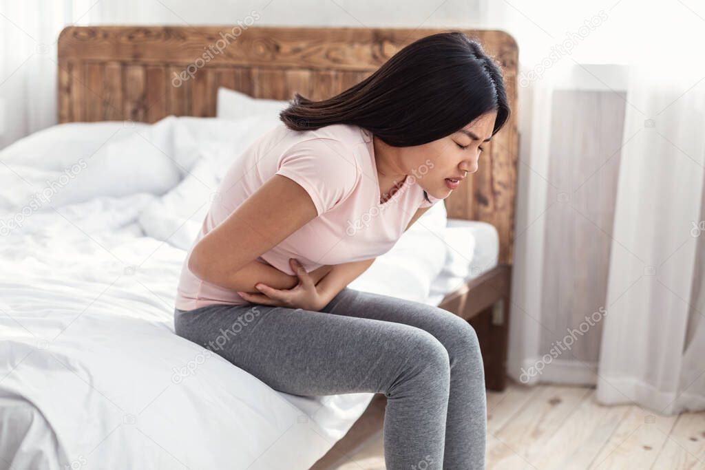 Asian Woman Having Stomachache Suffering From Pain Sitting At Home