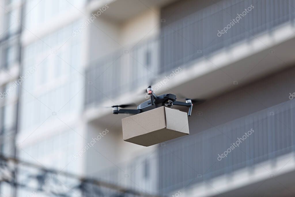 Flying Drone holding parcel. Air Delivery through the city