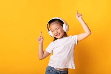 Gülümseyen Asyalı kız kulaklıkla müzik dinlemekten hoşlanıyor