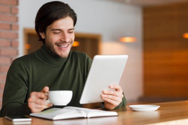 Freelancer kafede sabah kahvesi içiyor, tabletten haberleri kontrol ediyor.
