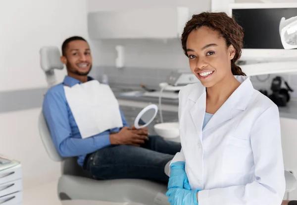 Odontólogo sonriente y paciente mirando a la cámara, interior del gabinete dental — Foto de Stock