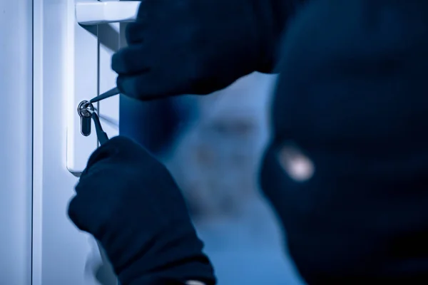 Ladrón en la puerta de la máscara de agrietamiento negro con picklock de metal —  Fotos de Stock