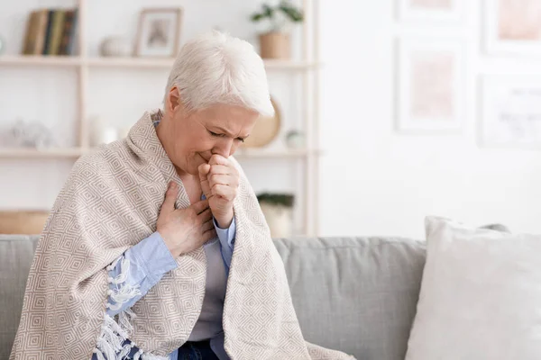Enferma mujer mayor cubierta en manta tosiendo duro en casa —  Fotos de Stock