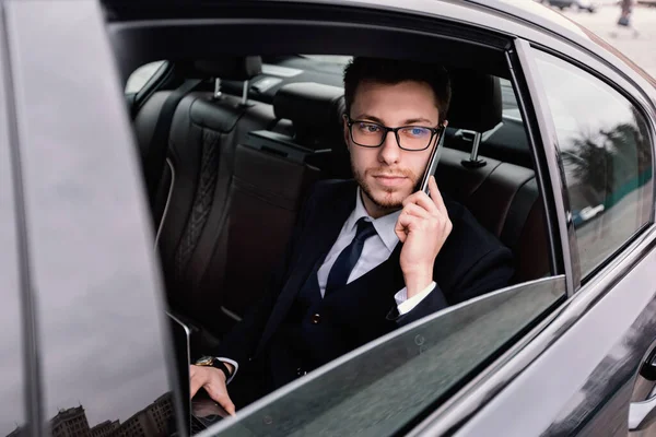 Jeune homme d'affaires parlant sur le téléphone intelligent dans la voiture — Photo
