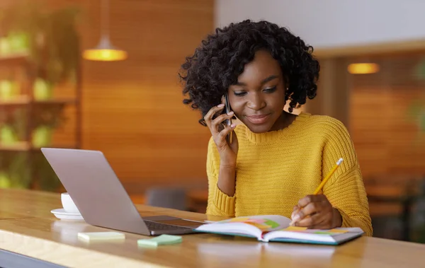 Business woman taking notes while talking with client on phone