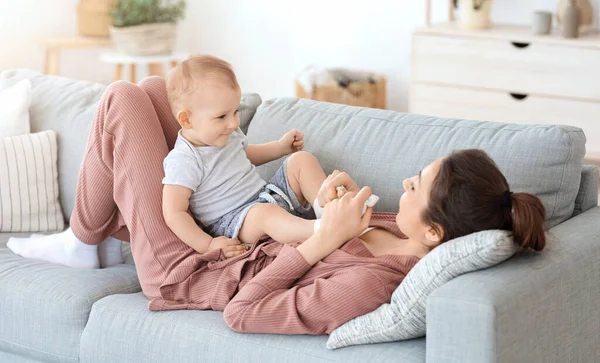 Młoda matka relaksująca się na kanapie ze swoim uroczym synkiem — Zdjęcie stockowe