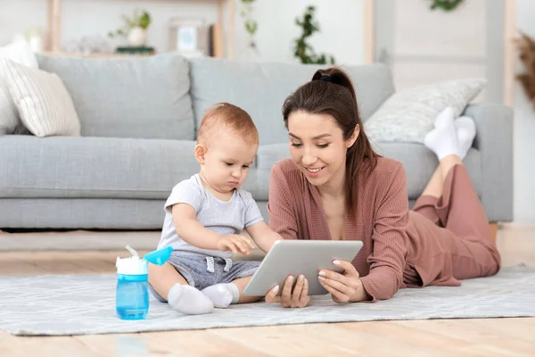 Feliz joven madre y adorable bebé niño usando tableta digital en casa — Foto de Stock