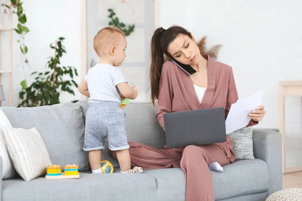 Zajęta mama pracuje w domu i spędza czas ze swoim niemowlęciem — Zdjęcie stockowe