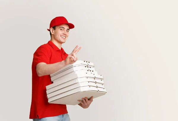 Sok pizzát hoztam haza. Mosolygó futár mutatja béke jel és tartja sok doboz — Stock Fotó