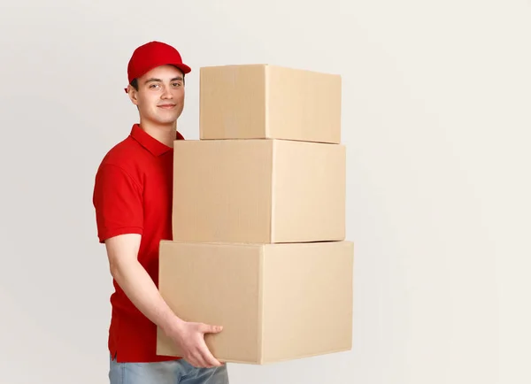 Muitas encomendas nos correios. Correio sorrindo detém um monte de parcelas — Fotografia de Stock