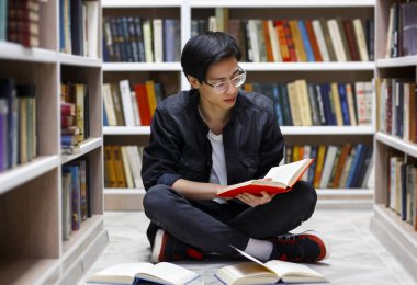 Kütüphanede kitap okuyan odaklanmış Çinli adam.