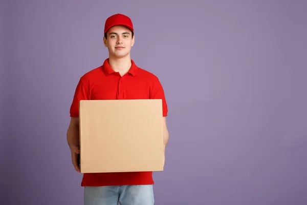 Převod balíků domů. Kurýr drží kartónovou krabici — Stock fotografie