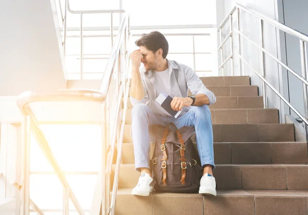 Reisebeschränkungen. Depressiver Mann sitzt auf Treppe im Flughafen, Flug abgesagt — Stockfoto