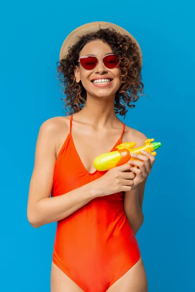 Brincalhão mulher africana se divertindo com brinquedos de verão, posando com arma de água — Fotografia de Stock