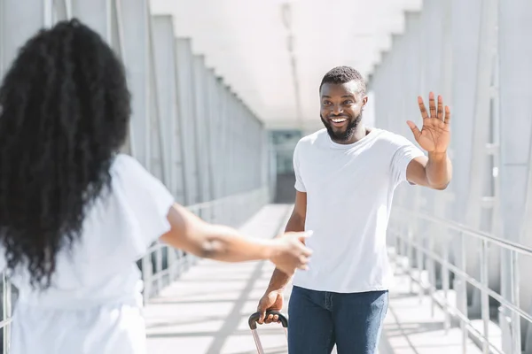 Glad afro man hälsar sin flickvän efter ankomsten till flygplatsen — Stockfoto