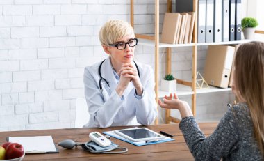 Hasta şikayetleri. Kadın doktor müşteriyi dikkatle dinler.