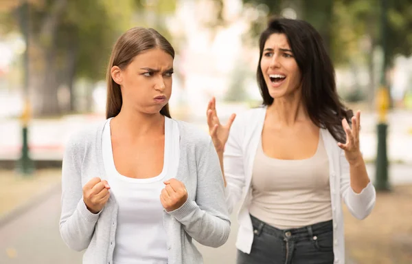 Две эмоциональные девушки-подруги конфликтуют, гуляя в парке — стоковое фото