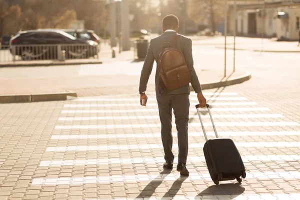 Uomo d'affari che attraversa la strada camminando con valigia in città, vista posteriore — Foto Stock