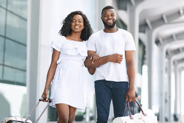 Retrato de feliz pareja africana posando cerca del edificio del aeropuerto antes de viajar — Foto de Stock